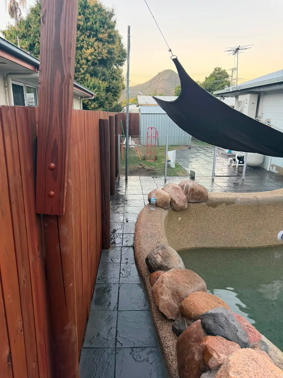 After: dark pavers along the fence and the same pool, seen from the other end