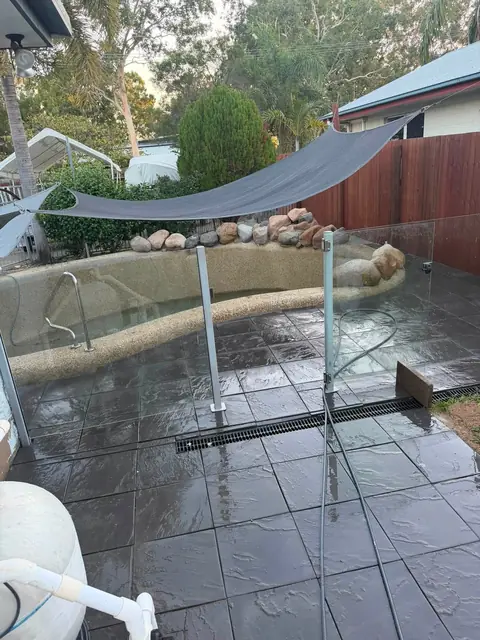 Dark paving around the pool, under a shade sail