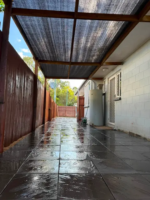 A paved side access under a pergola